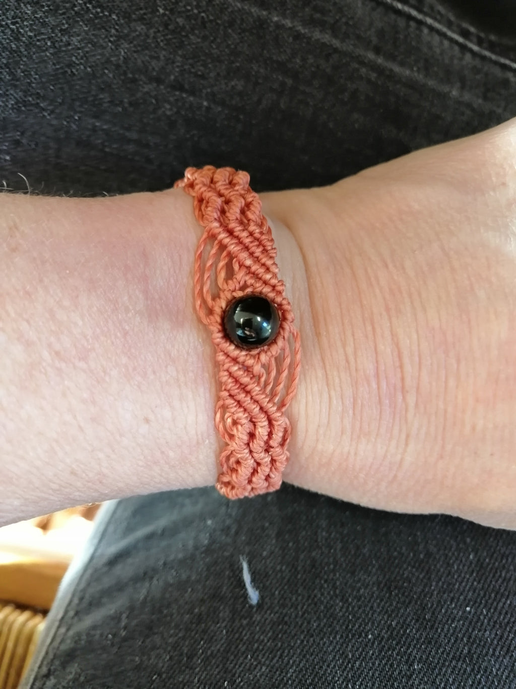bracelet modèle @solyluna tissé a la main en micro macramé de couleur brique avec une perle en obsidienne.