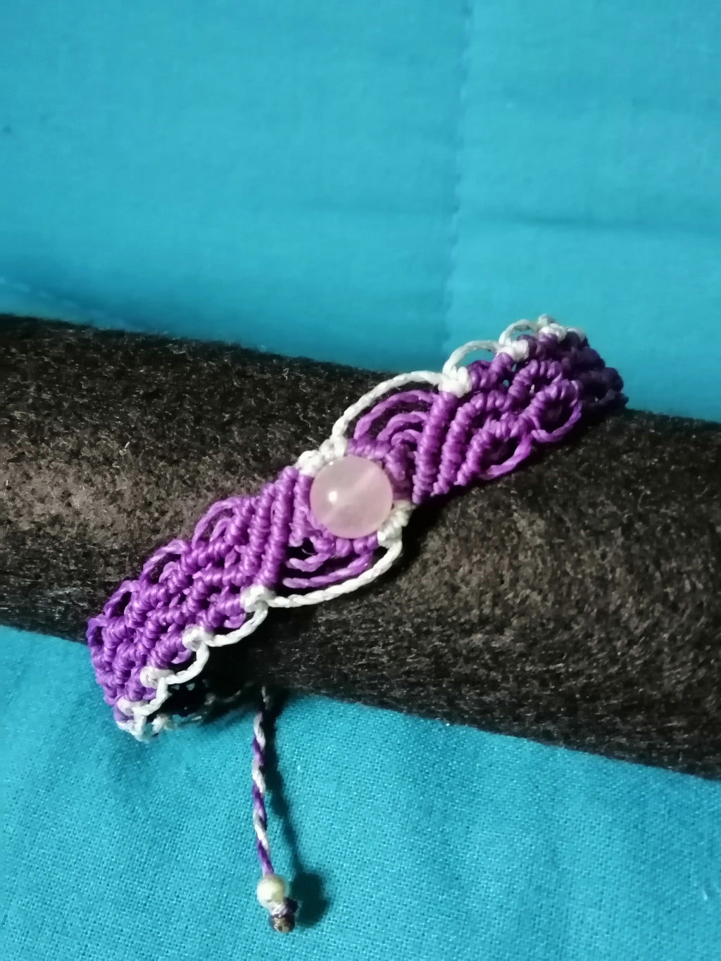 bracelet modèle @solyluna tissé a la main en micro macramé de couleur violet et argenté avec une perle en quartz rose.