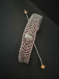 bracelet tissé a la main en micro macramé de couleur gris avec une perle en yooperlite.