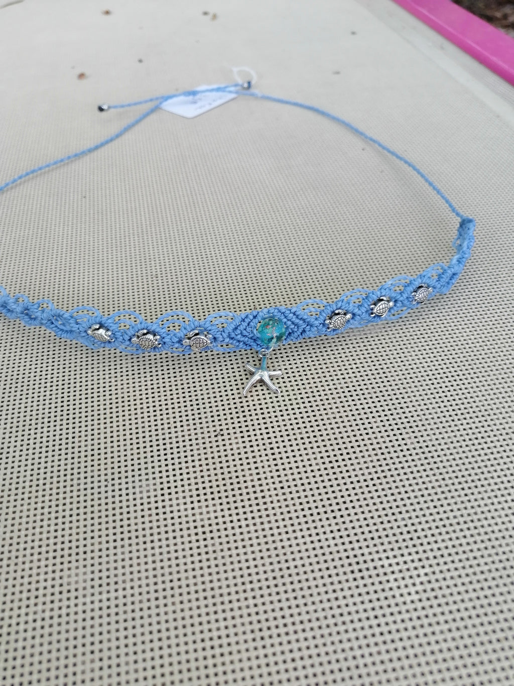 choker tissé à la main en micro macramé de couleur bleu ciel avec 3 tortue de chaque coté et en son centre une perle fluorescente de couleur bleu de 8mm avec une étoile de mer