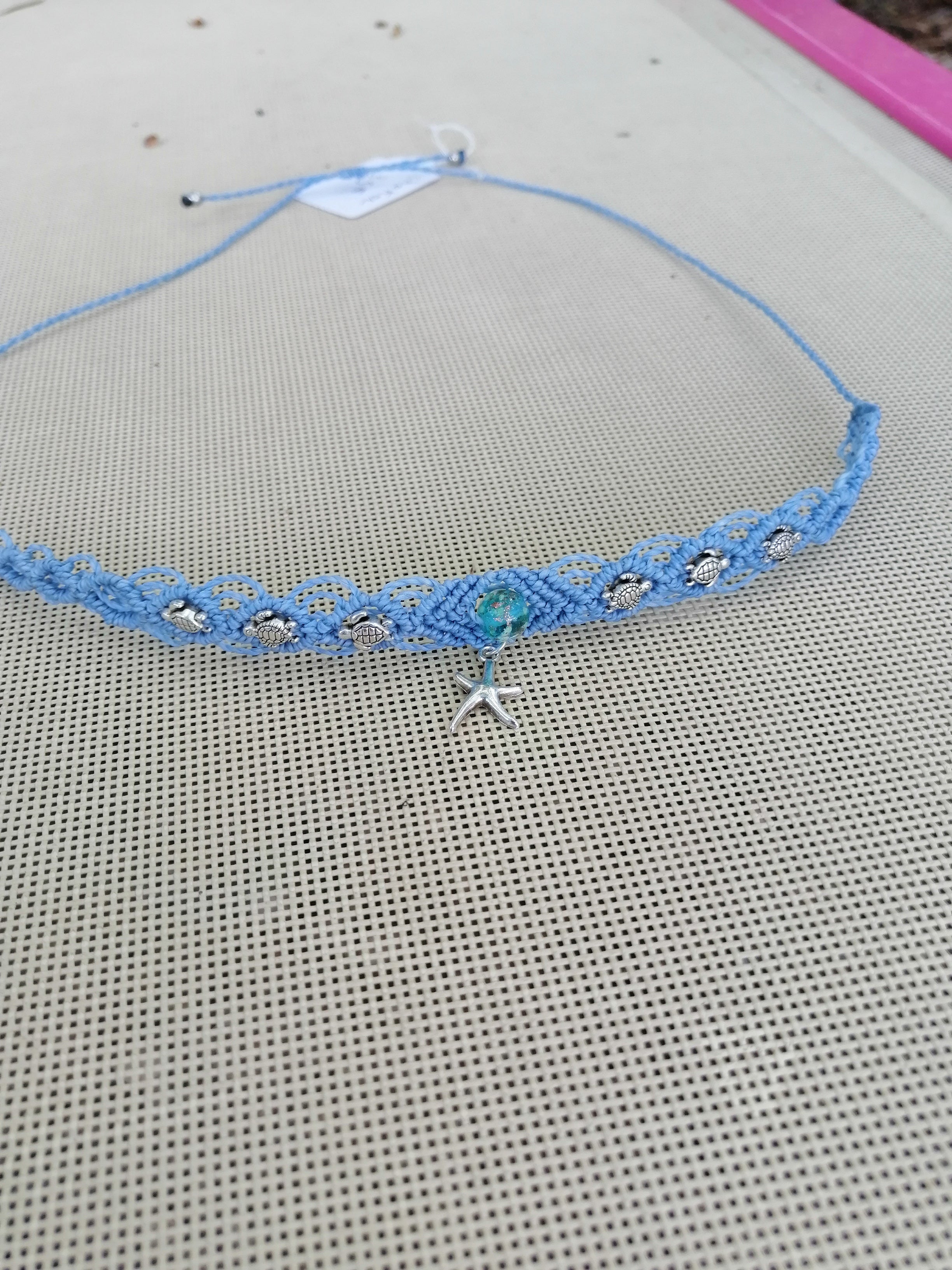 choker tissé à la main en micro macramé de couleur bleu ciel avec 3 tortue de chaque coté et en son centre une perle fluorescente de couleur bleu de 8mm avec une étoile de mer