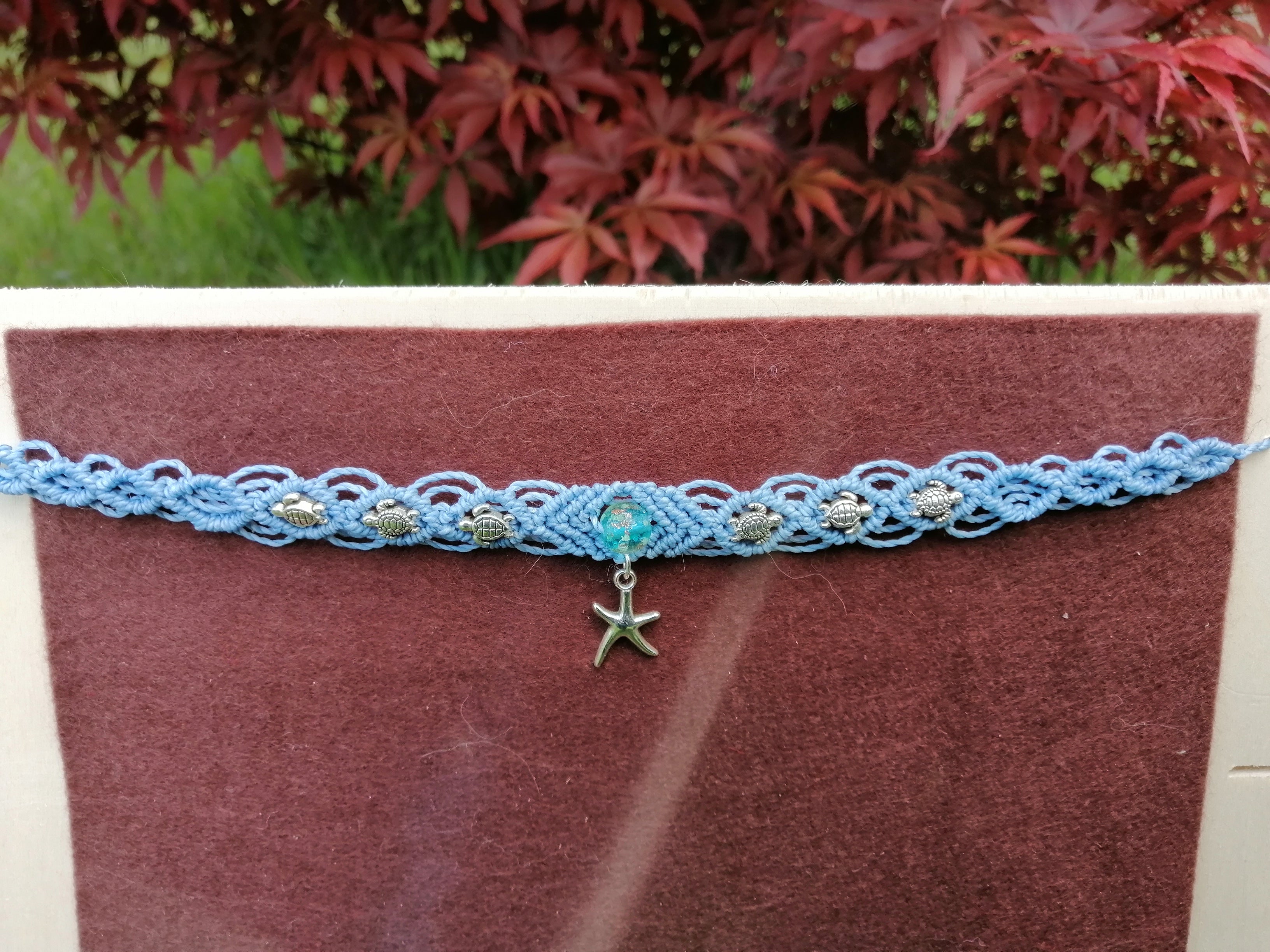 choker tissé à la main en micro macramé de couleur bleu ciel avec 3 tortue de chaque coté , une perle fluorescente bleu de 8mm et une étoile de mer