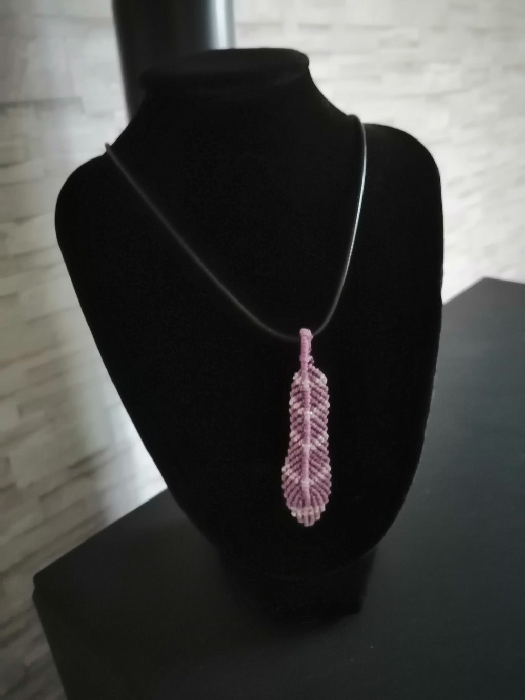 cordon en cuir noir avec une plume tissé a la main en micro macramé de couleur mauve et argenté.